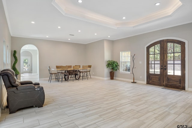 foyer entrance featuring a tray ceiling, a wealth of natural light, french doors, and ornamental molding