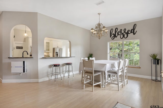 dining space featuring light wood-type flooring, an inviting chandelier, and sink