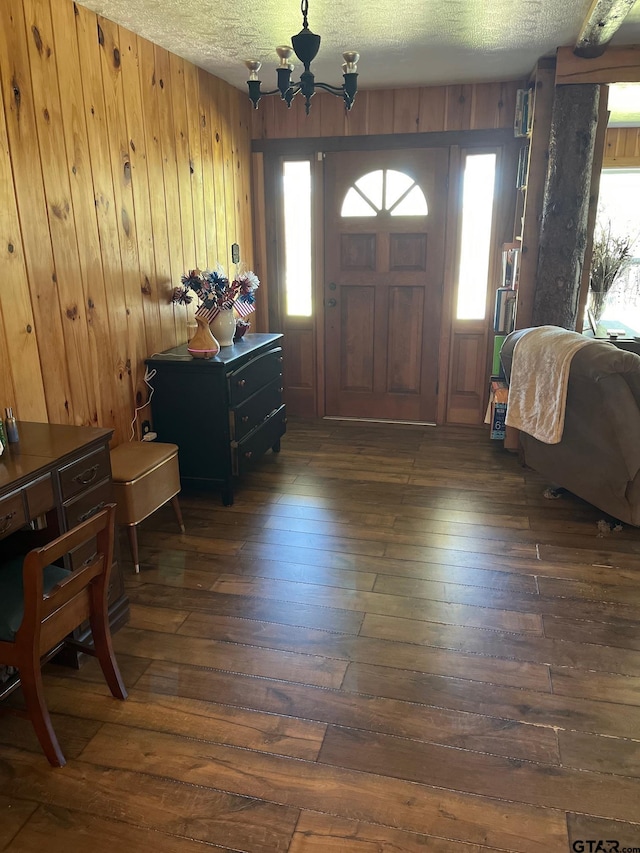 entrance foyer featuring hardwood / wood-style flooring, wooden walls, a chandelier, and a textured ceiling