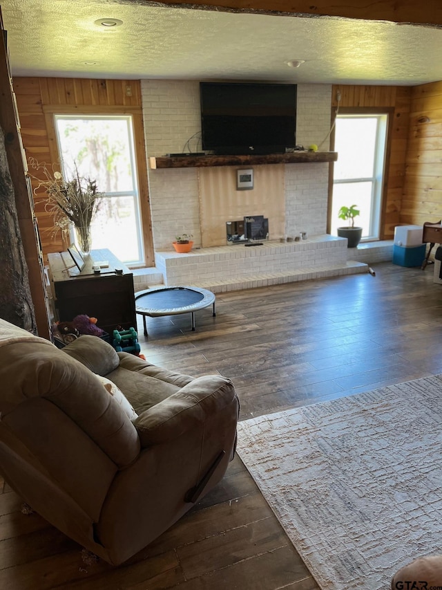 living area with a textured ceiling, wood finished floors, and wooden walls