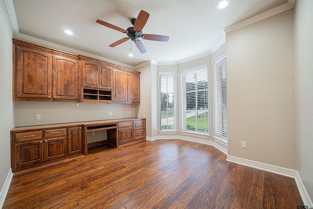 unfurnished office with ornamental molding, ceiling fan, built in desk, and dark hardwood / wood-style floors