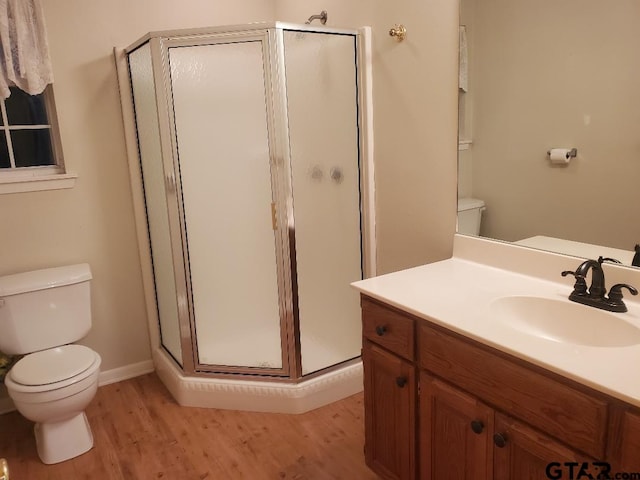 bathroom with wood-type flooring, vanity, toilet, and a shower with shower door