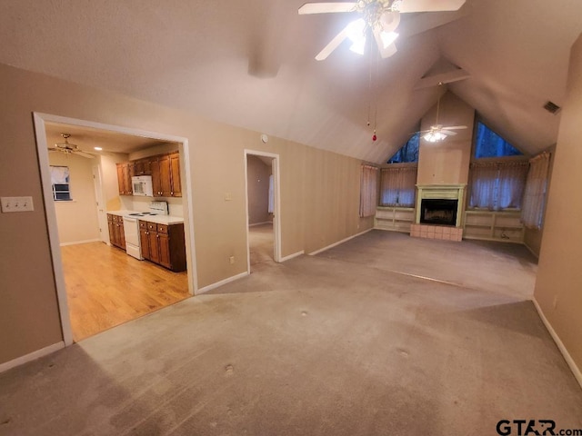 unfurnished living room featuring a large fireplace, light colored carpet, vaulted ceiling, and ceiling fan