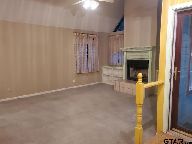 unfurnished living room featuring carpet, vaulted ceiling, ceiling fan, and a tiled fireplace