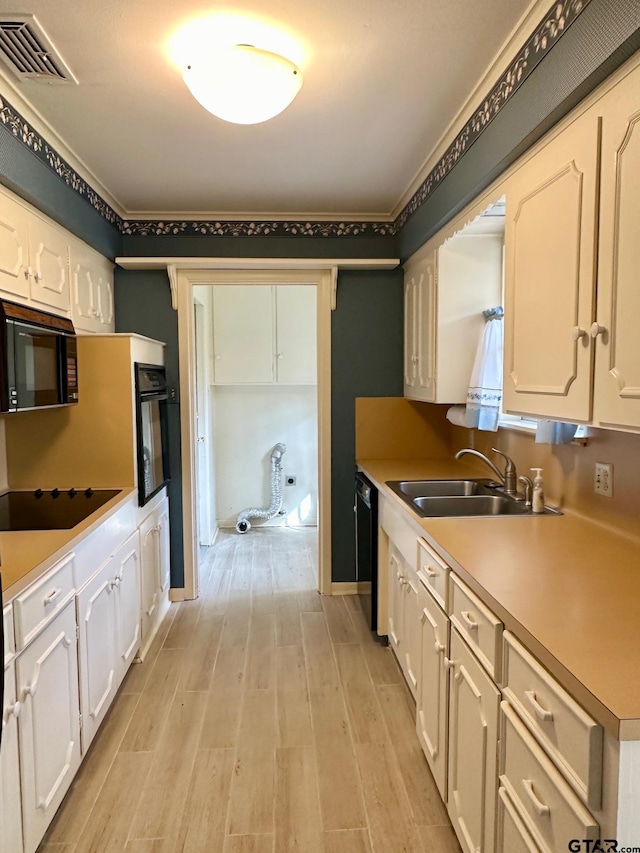 kitchen with white cabinets, sink, light hardwood / wood-style flooring, and black appliances