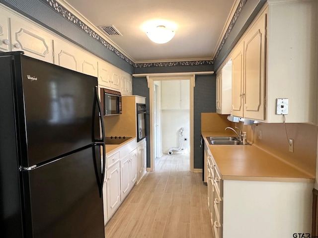 kitchen with light wood-type flooring, sink, white cabinetry, and black appliances