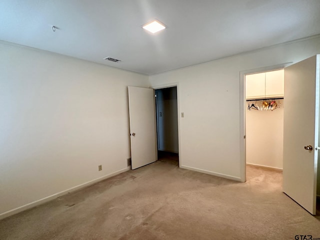 unfurnished bedroom featuring light colored carpet, a spacious closet, and a closet