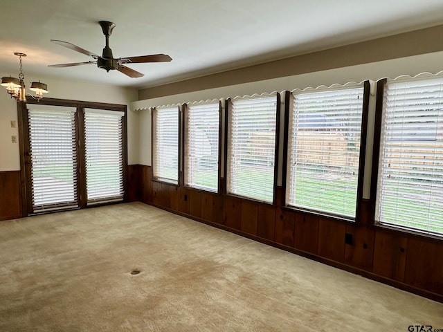 unfurnished sunroom featuring ceiling fan with notable chandelier