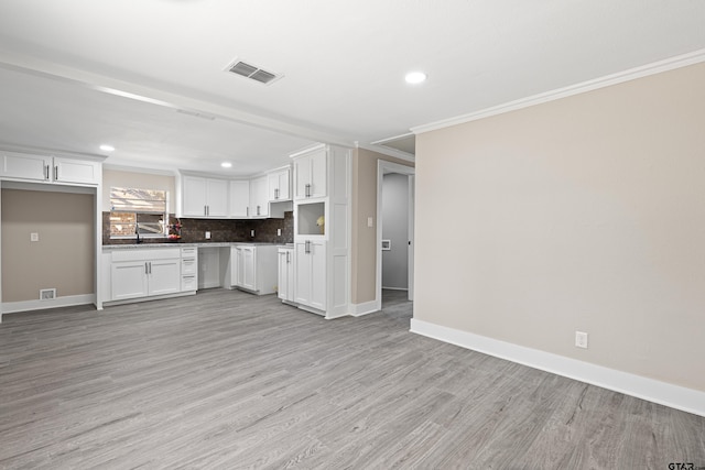 kitchen featuring ornamental molding, light wood-type flooring, decorative backsplash, and white cabinets