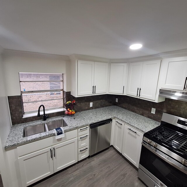 kitchen with white cabinetry, appliances with stainless steel finishes, sink, and light stone counters