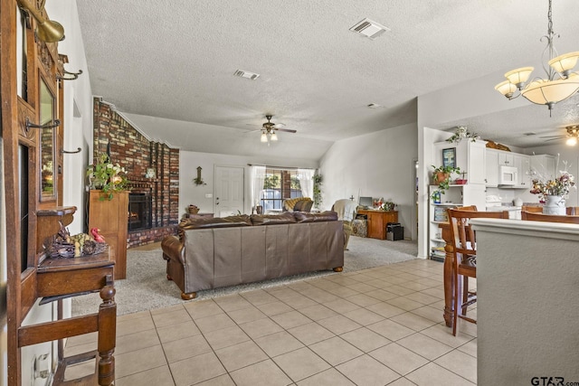 tiled living room featuring lofted ceiling, a brick fireplace, ceiling fan with notable chandelier, and a textured ceiling