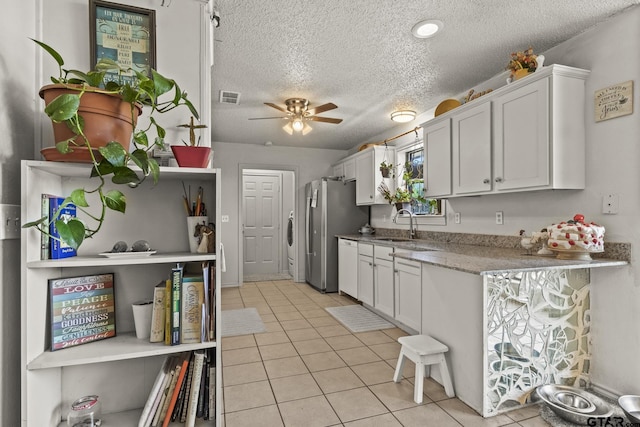 kitchen with light tile patterned flooring, sink, white cabinets, ceiling fan, and a textured ceiling