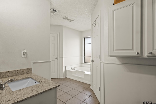 bathroom with tile patterned floors, a tub to relax in, a textured ceiling, and vanity