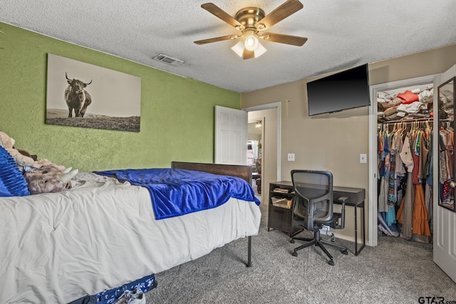 carpeted bedroom with ceiling fan, a spacious closet, a textured ceiling, and a closet