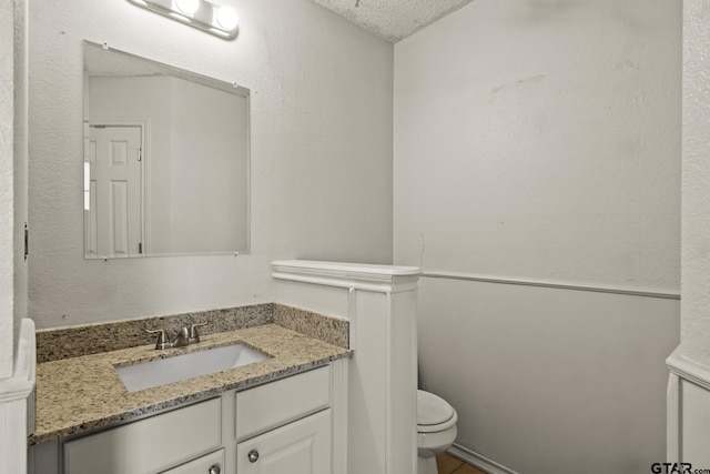 bathroom with vanity, a textured ceiling, and toilet