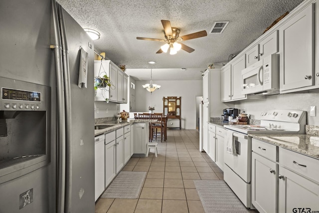 kitchen featuring hanging light fixtures, white appliances, and white cabinets