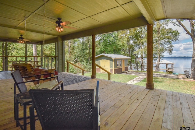 wooden terrace with an outbuilding, a water view, and ceiling fan