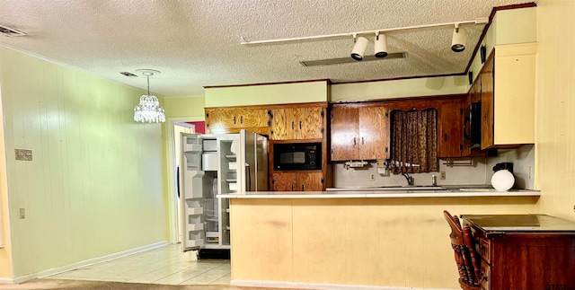 kitchen featuring black microwave, a textured ceiling, decorative light fixtures, and ornamental molding