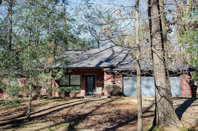 view of front of property with a garage, brick siding, driveway, and a shingled roof