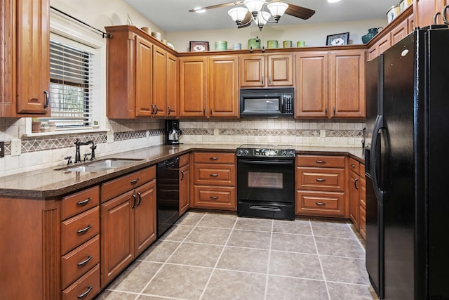 kitchen featuring a sink, brown cabinets, black appliances, and dark stone countertops