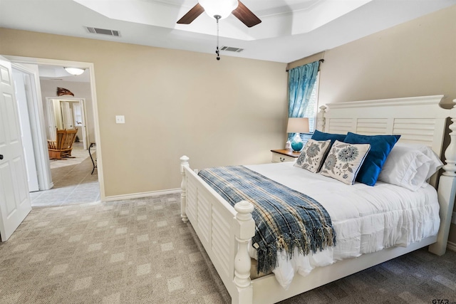 bedroom with light carpet, visible vents, a raised ceiling, and a ceiling fan