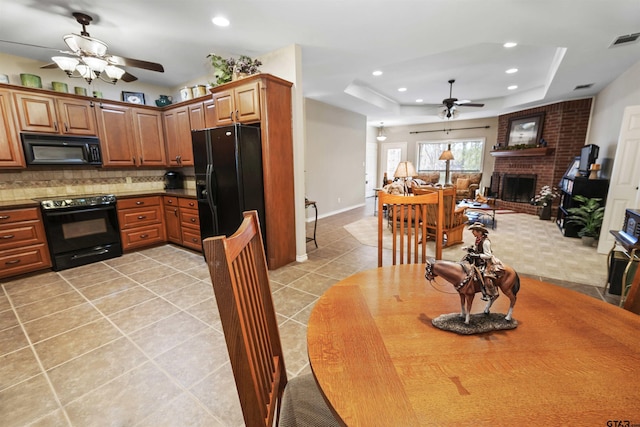 kitchen featuring a tray ceiling, black appliances, ceiling fan, and visible vents