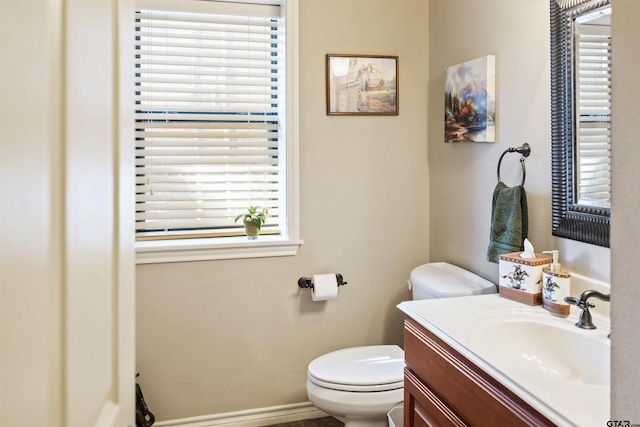 half bath with toilet, vanity, and baseboards