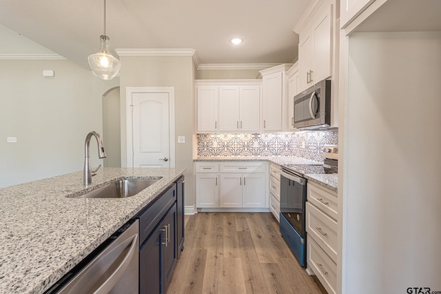 kitchen with hanging light fixtures, appliances with stainless steel finishes, sink, and white cabinets