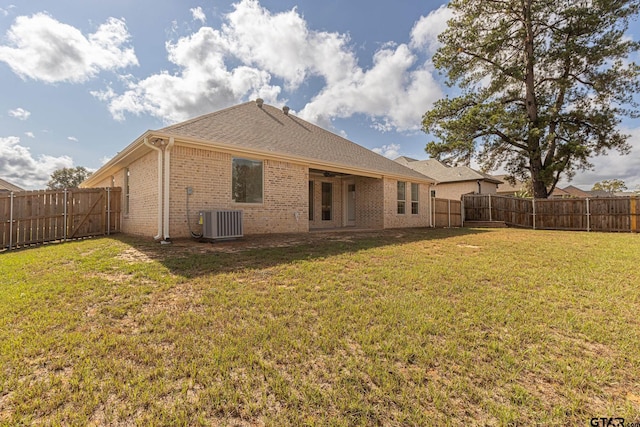 rear view of property featuring a yard and cooling unit