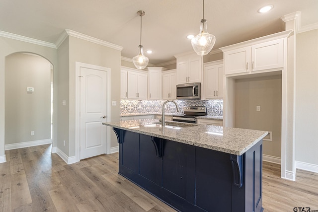 kitchen with sink, stainless steel appliances, light stone countertops, an island with sink, and white cabinets