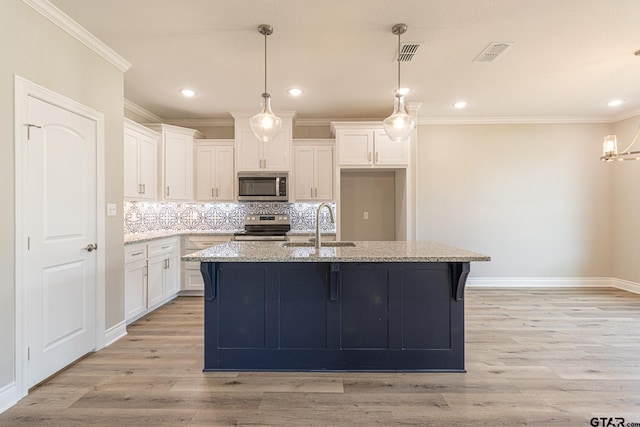 kitchen featuring stainless steel appliances, white cabinetry, light stone countertops, and a kitchen island with sink