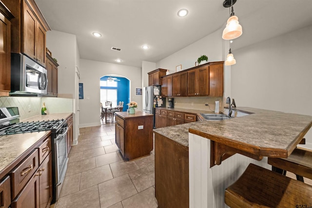 10926 Westhaven Cir, Flint, TX 75762 - kitchen with appliances with stainless steel finishes, a center island, arched walkways, decorative backsplash, and a peninsula
