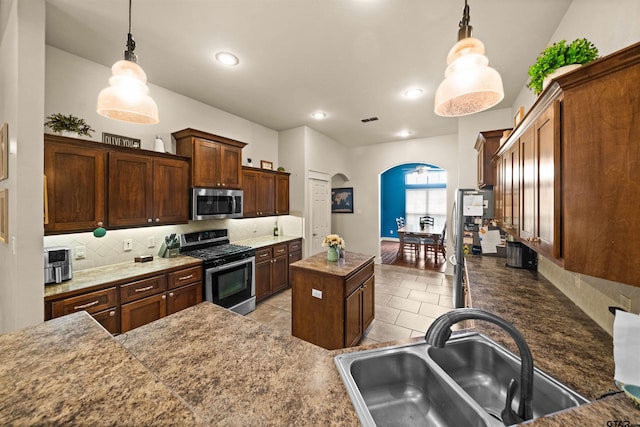10926 Westhaven Cir, Flint, TX 75762 - kitchen featuring appliances with stainless steel finishes, arched walkways, a center island, tasteful backsplash, and light tile patterned flooring