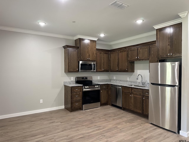 kitchen with a sink, visible vents, stainless steel appliances, dark brown cabinets, and ornamental molding