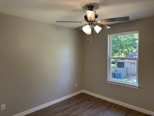 empty room featuring baseboards, a ceiling fan, and dark wood-style floors