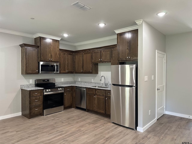 kitchen with a sink, stainless steel appliances, dark brown cabinetry, visible vents, and baseboards