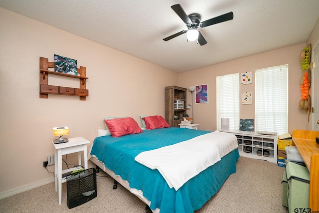 carpeted bedroom featuring ceiling fan and a textured ceiling