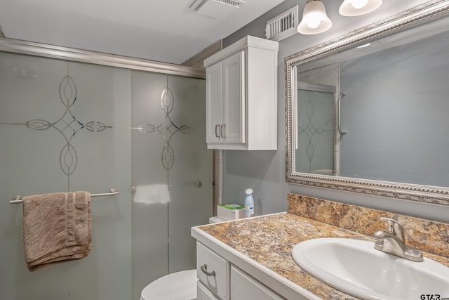 bathroom with a shower with shower door, vanity, and toilet