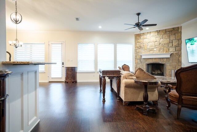 living room with dark hardwood / wood-style flooring, crown molding, a fireplace, and ceiling fan with notable chandelier