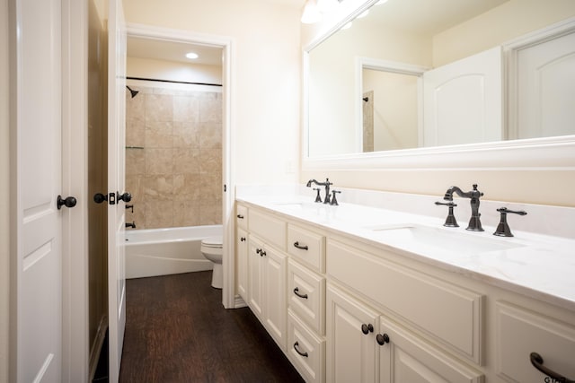 full bathroom with hardwood / wood-style floors, vanity, toilet, and tiled shower / bath combo