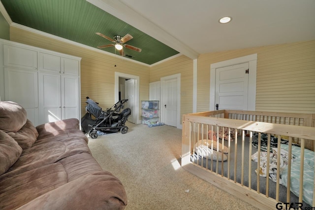 carpeted bedroom with a closet, ceiling fan, ornamental molding, and beam ceiling