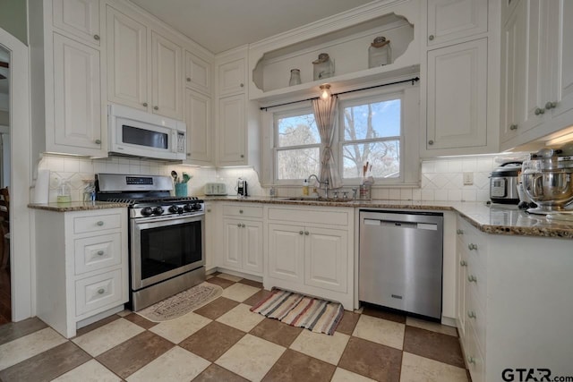 kitchen with decorative backsplash, stainless steel appliances, white cabinetry, and light stone countertops