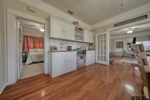 kitchen with white cabinetry, french doors, light wood-type flooring, ornamental molding, and ceiling fan