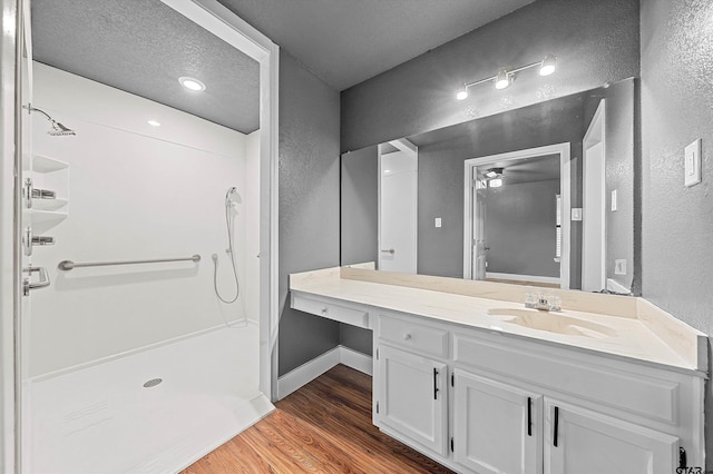 bathroom featuring a textured ceiling, vanity, hardwood / wood-style flooring, and a shower