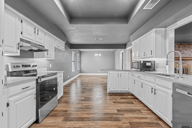 kitchen with white cabinets, kitchen peninsula, appliances with stainless steel finishes, and a textured ceiling