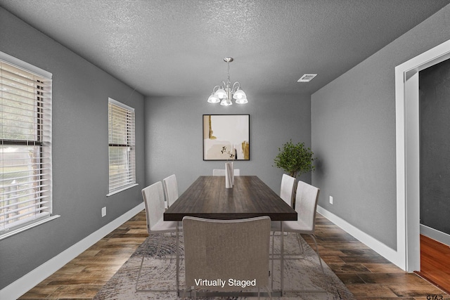 dining space featuring dark hardwood / wood-style flooring, a chandelier, and a textured ceiling