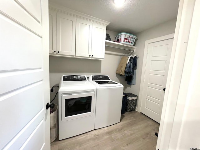 washroom featuring light wood-type flooring, washing machine and dryer, and cabinet space