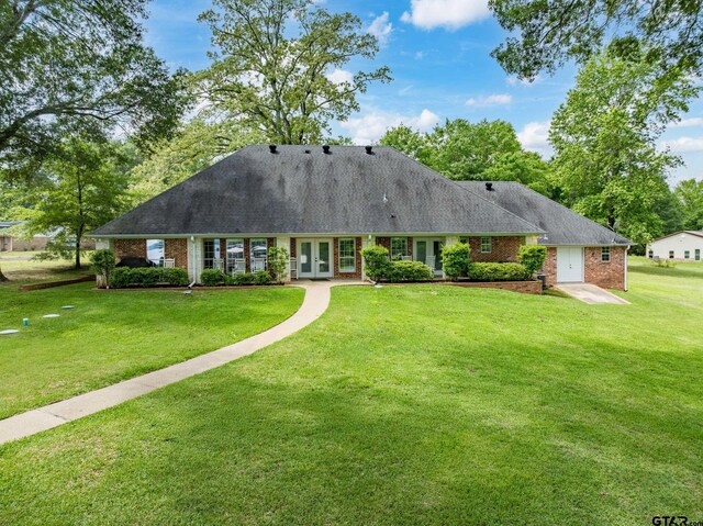 view of front facade with brick siding, french doors, and a front yard