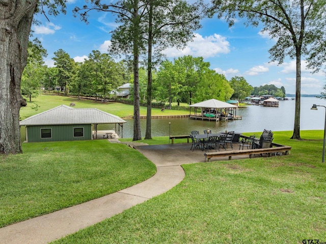 view of home's community with a water view, a yard, and a dock