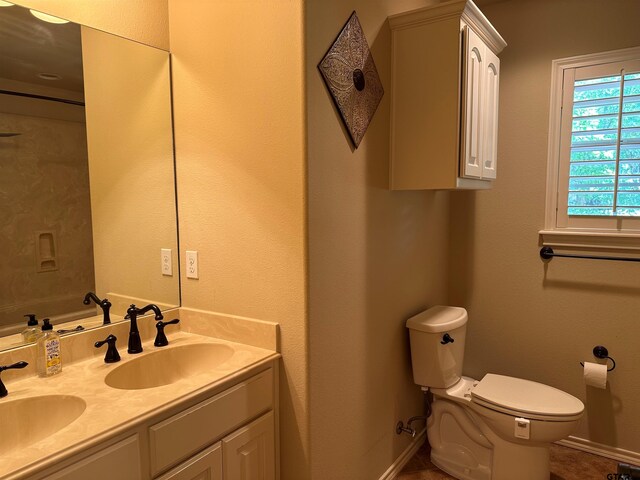 bathroom featuring a sink, baseboards, toilet, and double vanity